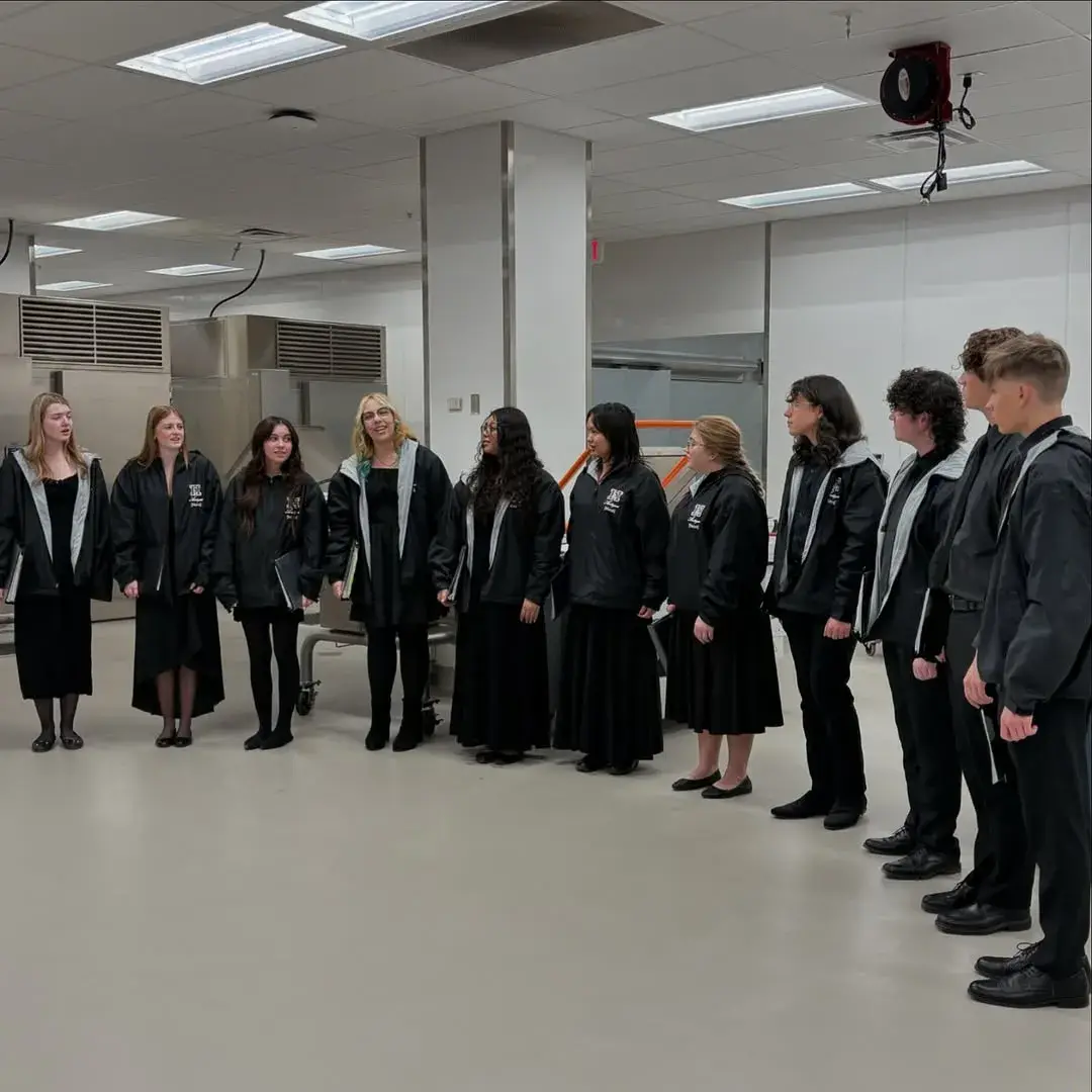Hamilton singers in black concert dress standing in a semicircle in a school hallway