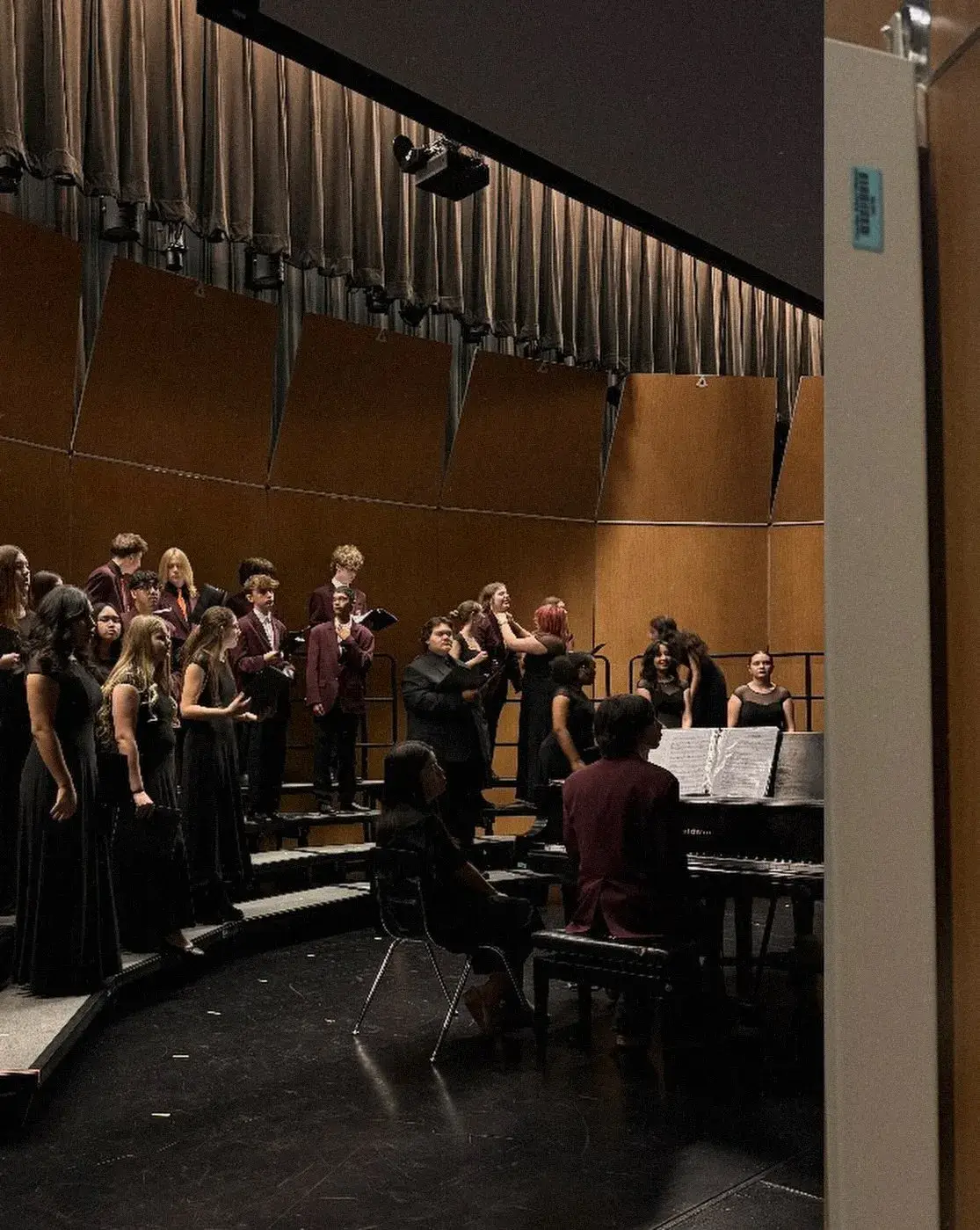 The choir on risers seen from the wings during a concert